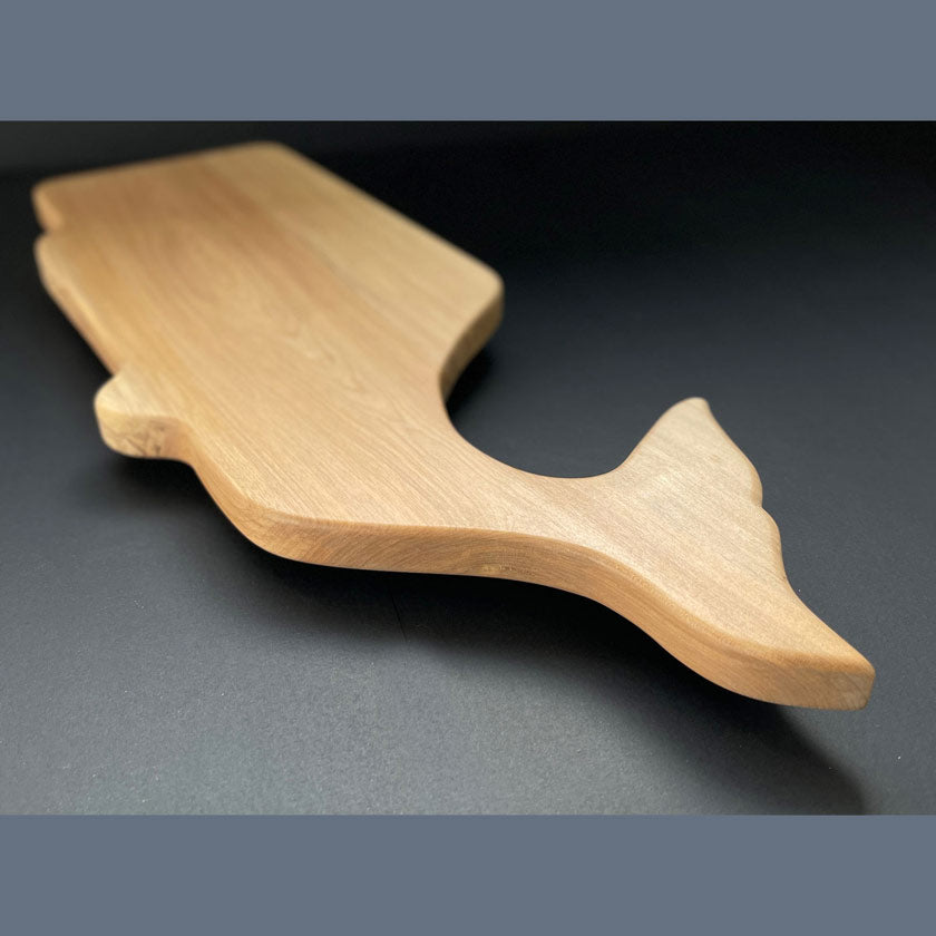 Profile of handcrafted whale board highlighting curved body and tail