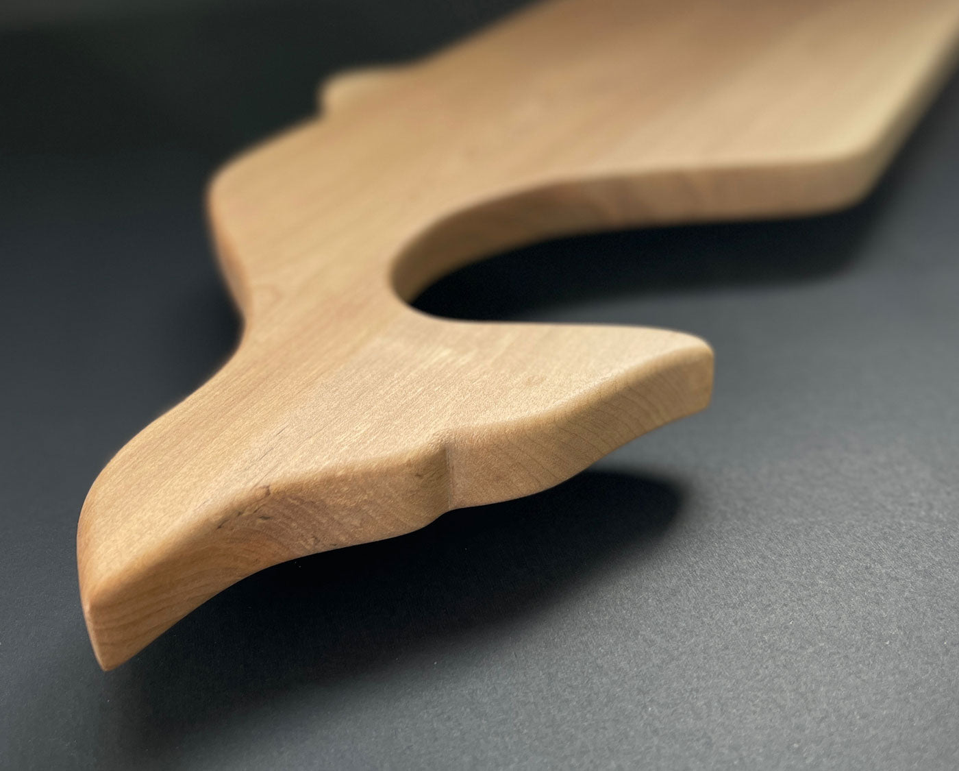 Detailed view of the whale tail carving on birch wood board