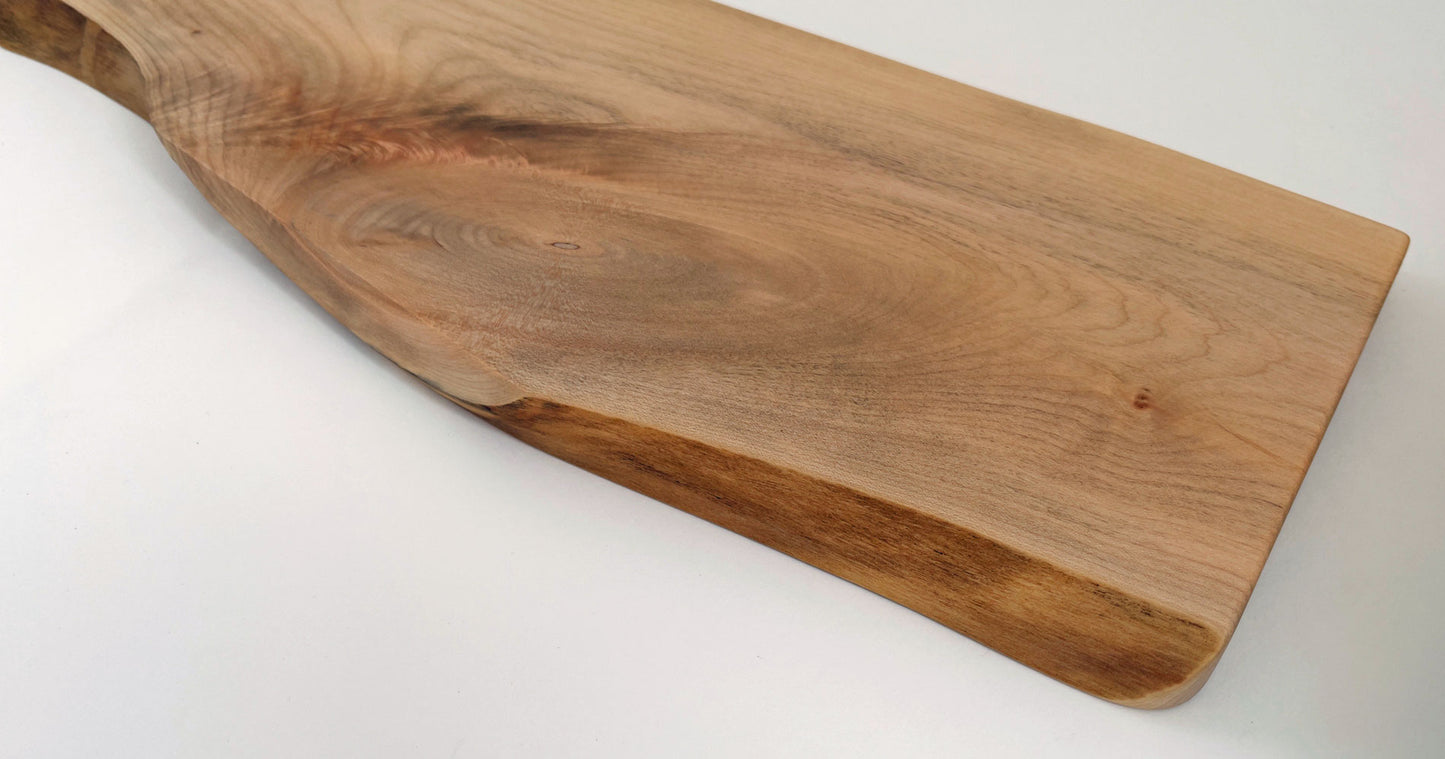 Handcrafted maple serving board with organic edge and rounded handle