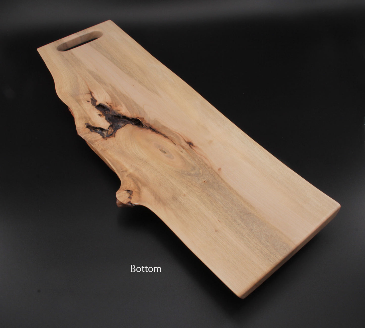 Live edge maple charcuterie board with integrated slot handle and rich wood grain