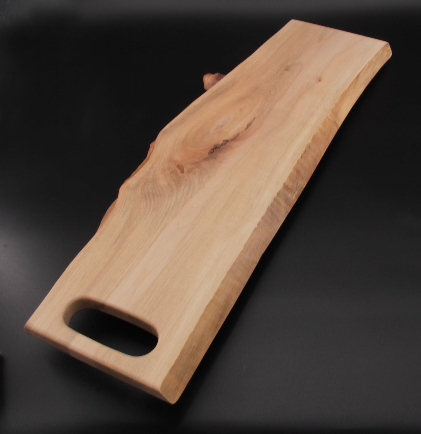 Live edge maple charcuterie board with integrated slot handle and rich wood grain