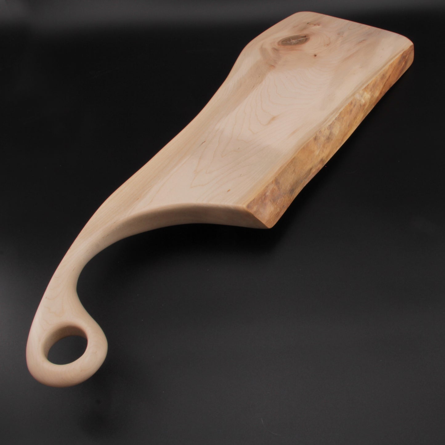 Side profile showing the board’s live edge and polished maple grain