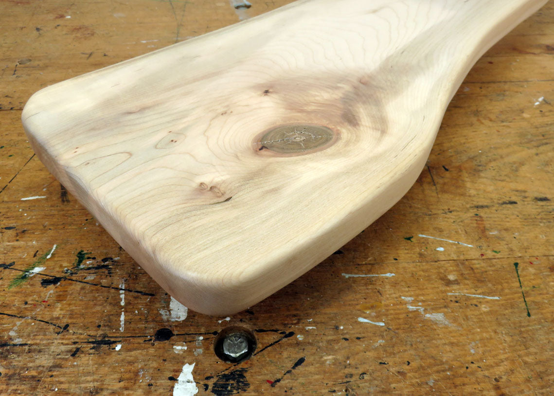 Handcrafted maple charcuterie board with live edge and sweeping handle featuring a hanging loop