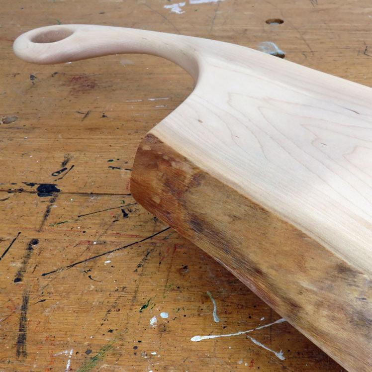 Handcrafted maple charcuterie board with live edge and sweeping handle featuring a hanging loop