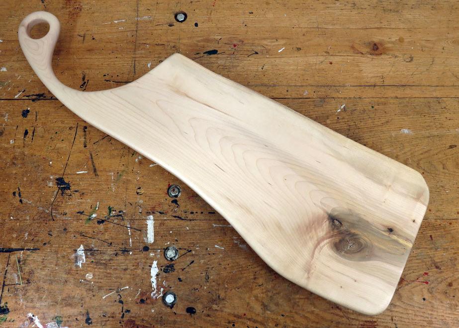 Handcrafted maple charcuterie board with live edge and sweeping handle featuring a hanging loop