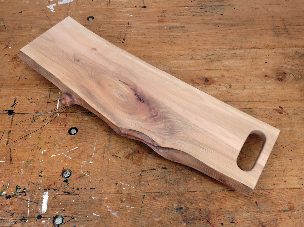 Live edge maple charcuterie board with integrated slot handle and rich wood grain