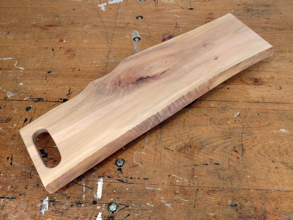 Live edge maple charcuterie board with integrated slot handle and rich wood grain
