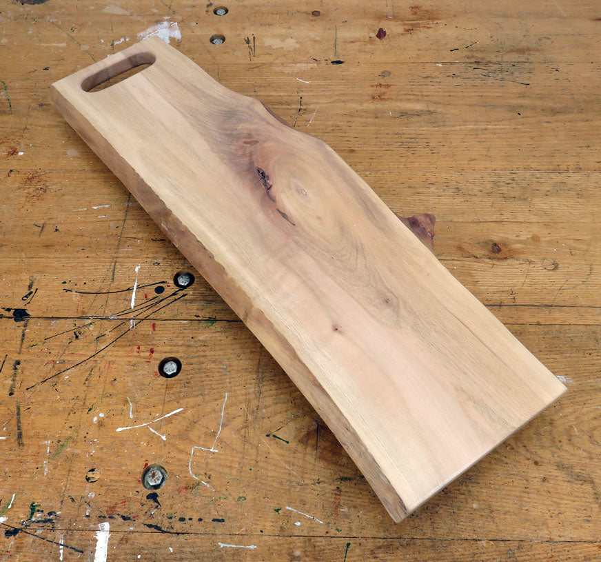 Live edge maple charcuterie board with integrated slot handle and rich wood grain