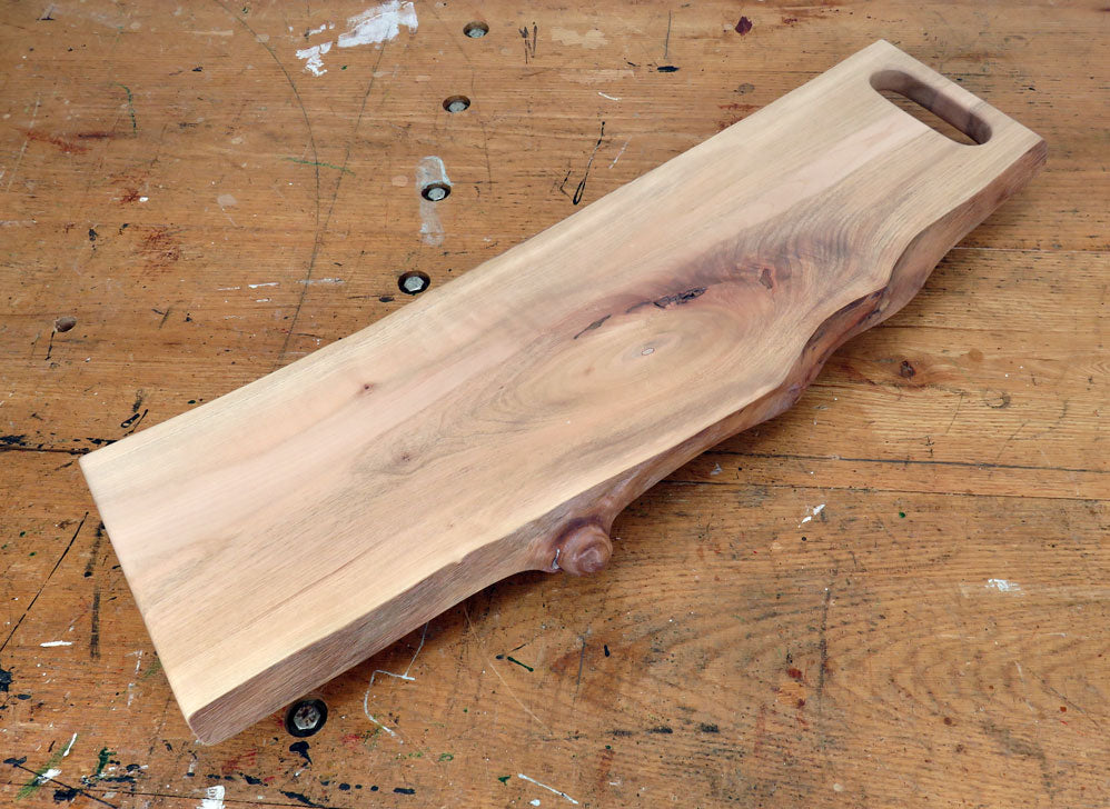 Live edge maple charcuterie board with integrated slot handle and rich wood grain