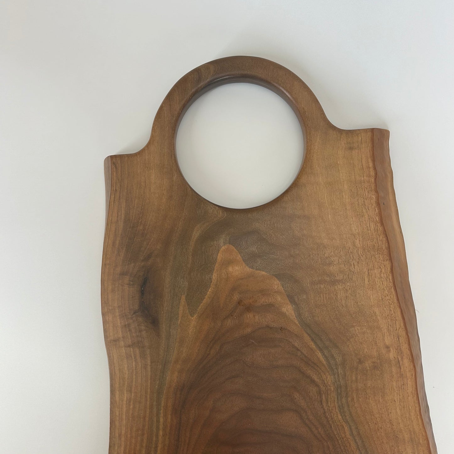 Oversized round handle carved into black walnut board for bold, functional design