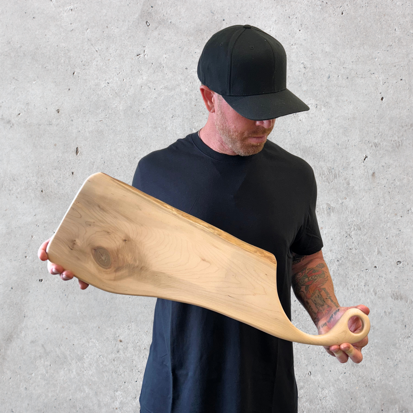 Handcrafted maple charcuterie board with live edge and sweeping handle featuring a hanging loop