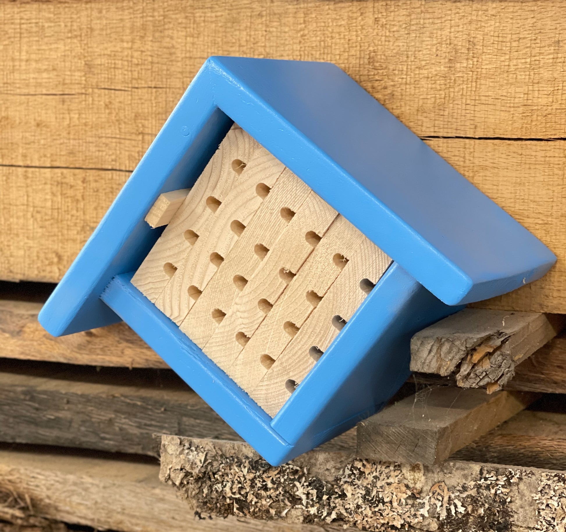 Front view of chalet bee house with sloped roof and nesting tunnels for solitary bees